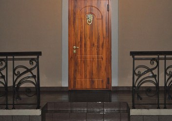 Квартирная дверь с наружной отделкой МДФ в пленке ПВХ и декоративной ручкой-стучалкой Лев.