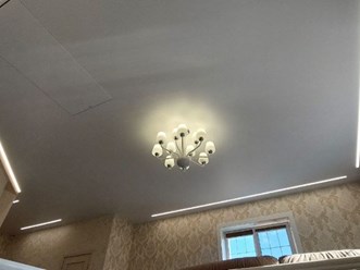 Натяжной потолок со световыми линиями и люстрой в гостинной