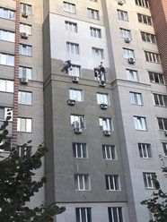 Альпинисты штукатурят фасад на высоте.