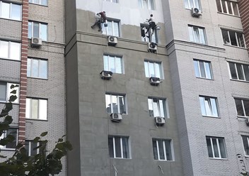 Альпинисты штукатурят фасад на высоте.