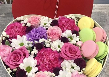 Романтичный подарок — это букет в коробочке формы сердца, наполненный ароматными цветами и сладким печеньем &quot;Макарони&quot;.