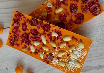 Плитка из апельсинового шоколада с добавлением орехов, ягод малины и кусочков вишни.
