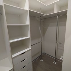 Вместительная белая гардеробная комната из ЛДСП с множеством полок, отсеков, ящиков.