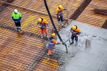 Бригада бетонщиков укладывает бетон в фундаментную плиту