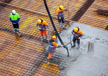 Бригада бетонщиков укладывает бетон в фундаментную плиту