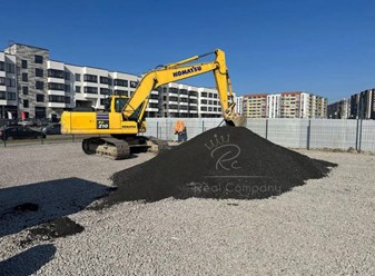 Погрузка асфальтовой крошки экскаватором Komatsu на строительной площадке. Переработка дорожного покрытия, вторичные материалы от Real Company для благоустройства территорий.