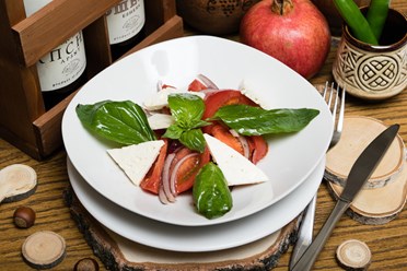Салат из ароматных узбекских помидор заправленные специальным соусом, приготовленным по особенному рецепту шеф повара, с нежнейшим сыром и свежими листочками базилика.