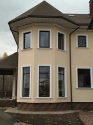 Современный красивый дом с нестандартными пластиковыми окнами большого размера ламинированными под темный дуб.