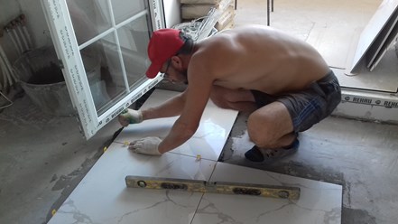 Плиточник за работой на отделке в новостройке
