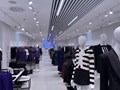 Готовый торговый зал магазина одежды после дизайнерского ремонта: рейлинговые потолки, LED-освещение, белая отделка стен, светлый керамогранит.