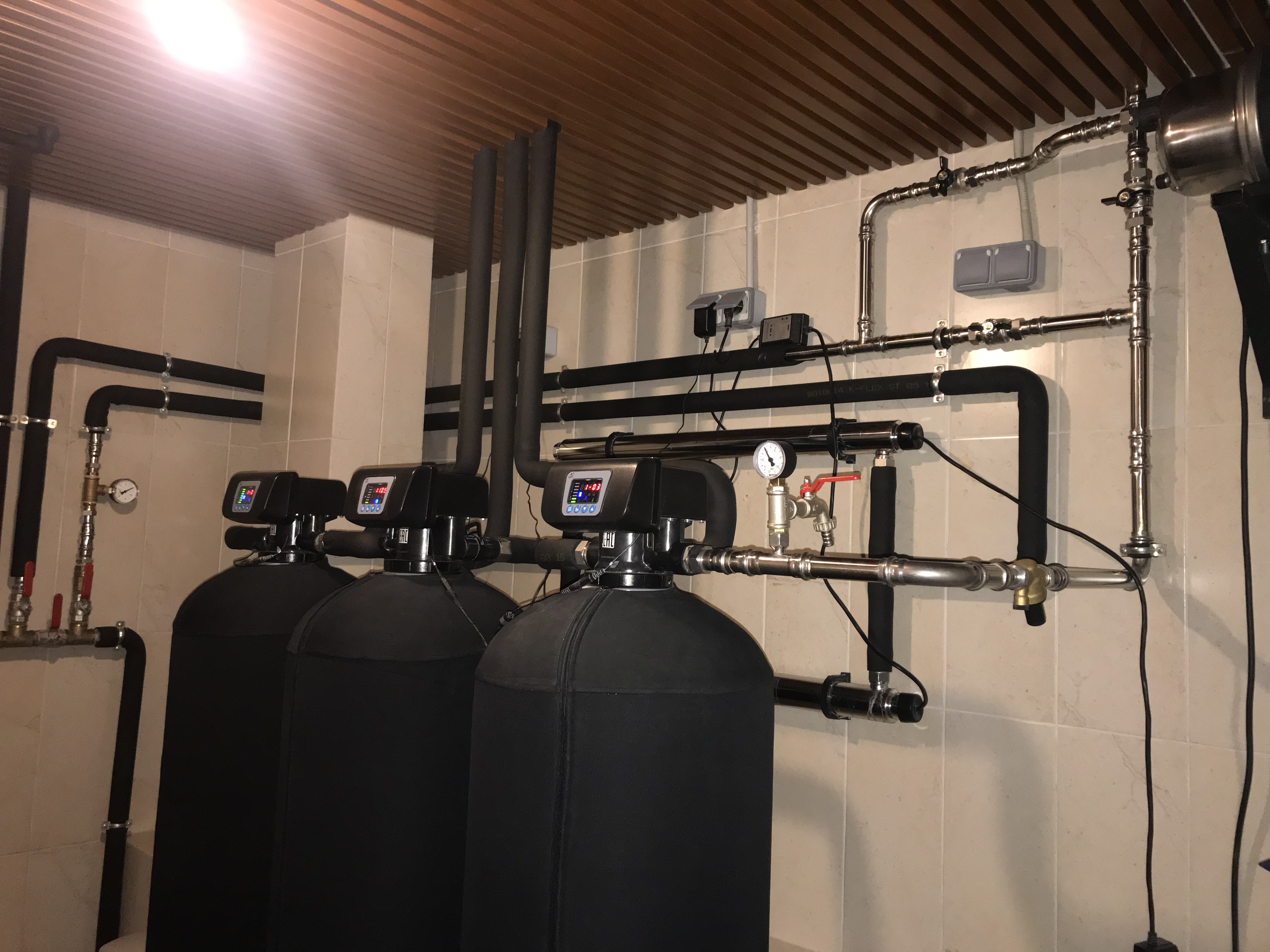 Монтаж стильной системы водоочистки. Фильтры и подводка выполнены в чёрном цвете с металлическими соединениями.